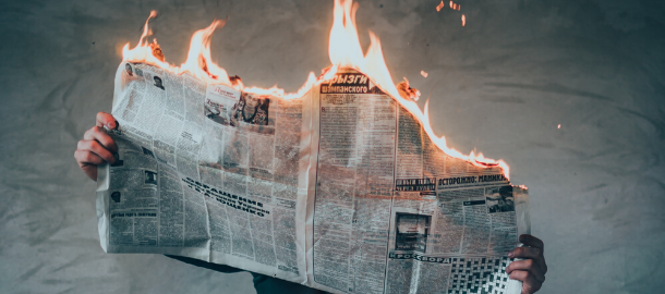 person holding newspaper on fire
